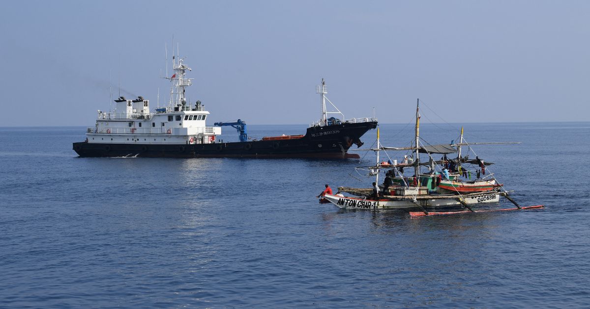 A Philippine fishing boat sails past a Chinese militia ship near the Scarborough Shoal in the disputed South China Sea on Sept. 20.