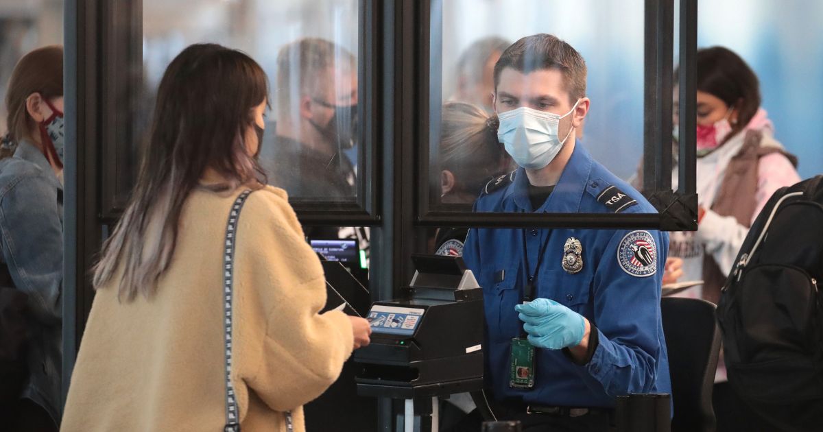 A Transportation Security Administration agent screens an airline passenger at O'Hare International Airport in October 2020 in Chicago, Illinois.