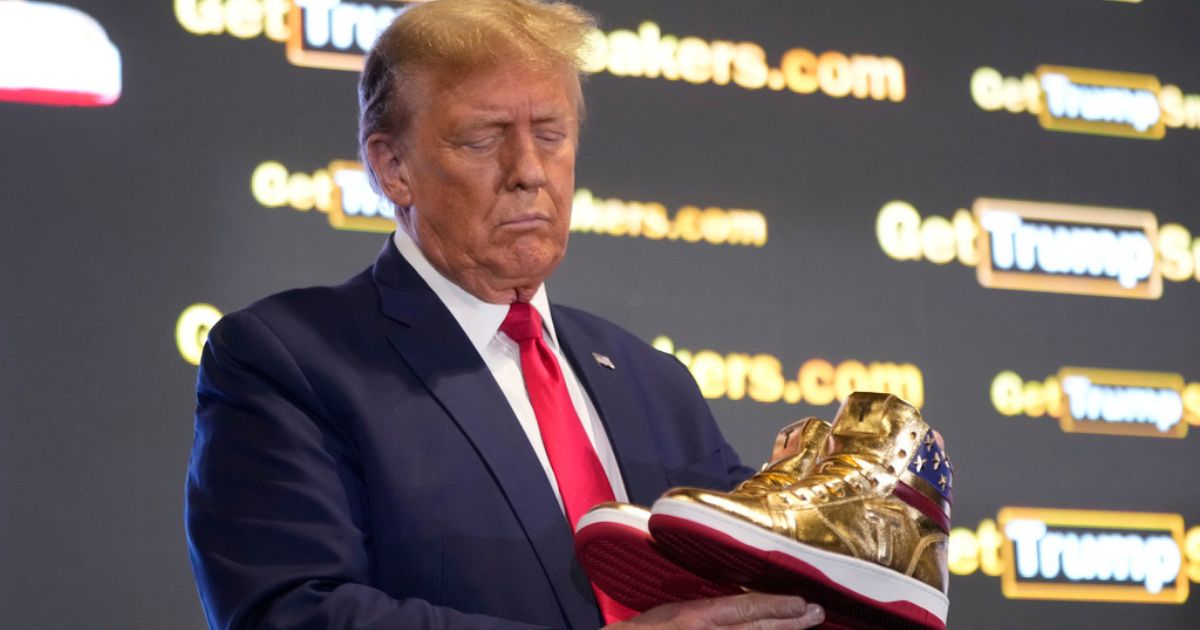 Republican presidential candidate former President Donald Trump holds gold Trump sneakers at Saturday's Sneaker Con Philadelphia, an event popular among sneaker collectors.