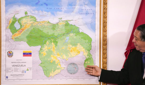Chairman of the Special Commission for the Defense of Guyana, Essequibo Hermann Escarra, stands next to Venezuela's new map that includes the Essequibo territory, a swath of land that is administered and controlled by Guyana but claimed by Venezuela.