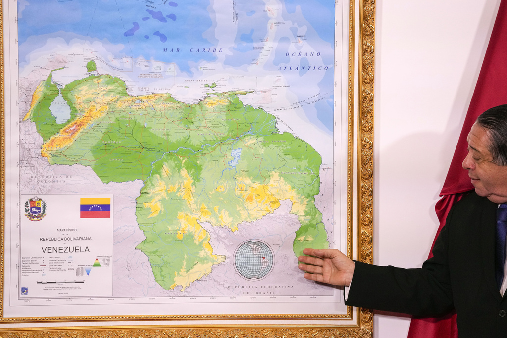 Chairman of the Special Commission for the Defense of Guyana, Essequibo Hermann Escarra, stands next to Venezuela's new map that includes the Essequibo territory, a swath of land that is administered and controlled by Guyana but claimed by Venezuela.