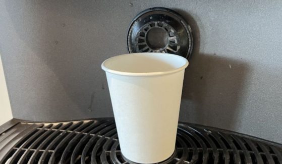 A paper cup is shown on a commercial coffee machine.