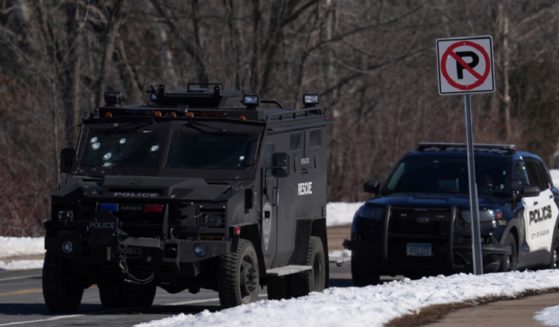 A police vehicle with bullet pockmarks on its windshield is parked near the scene where two police officers and a firefighter/paramedia were shot and killed Sunday in Burnsville, Minnesota.