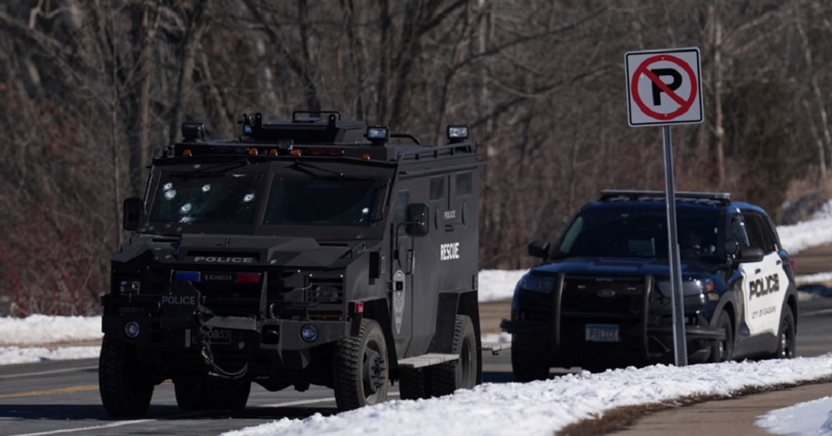 A police vehicle with bullet pockmarks on its windshield is parked near the scene where two police officers and a firefighter/paramedia were shot and killed Sunday in Burnsville, Minnesota.