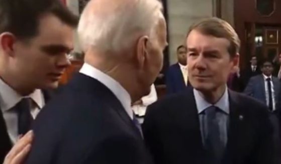 While President Joe Biden, center, spoke with Colorado Sen. Michael Bennet, right, after Thursday's State of the Union address, a Biden aide, left, informed the president his microphone was live.