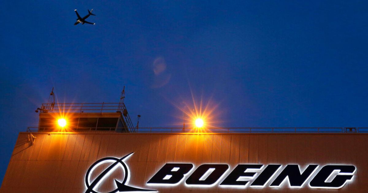 An airplane flies over a sign on Boeing's 737 delivery center at Boeing Field in Seattle.