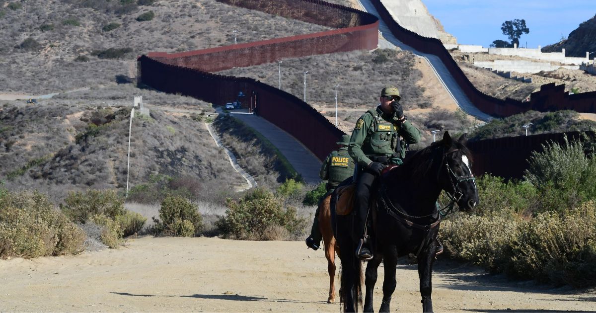 U.S. Border Patrol police on horseback monitor the U.S.-Mexico border fence in Imperial Beach, California, on Nov. 7, 2021.