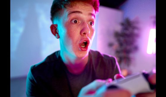 A man with a surprised expression on his face holding a video game controller.