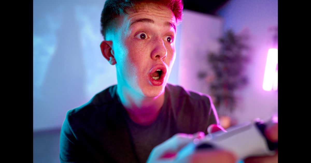 A man with a surprised expression on his face holding a video game controller.