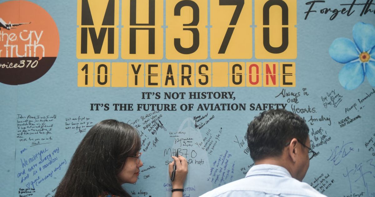 A woman writes a message during Sunday's event to mark the 10th year since the Malaysia Airlines flight MH370 carrying 239 people disappeared from radar screens on March 8, 2014, while en route from Kuala Lumpur to Beijing.