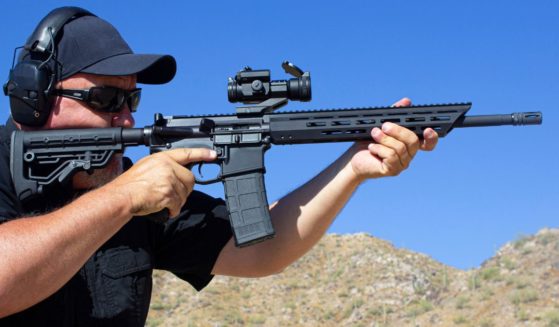 A stock photo shows a man firing an AR-15-style rifle at a range.