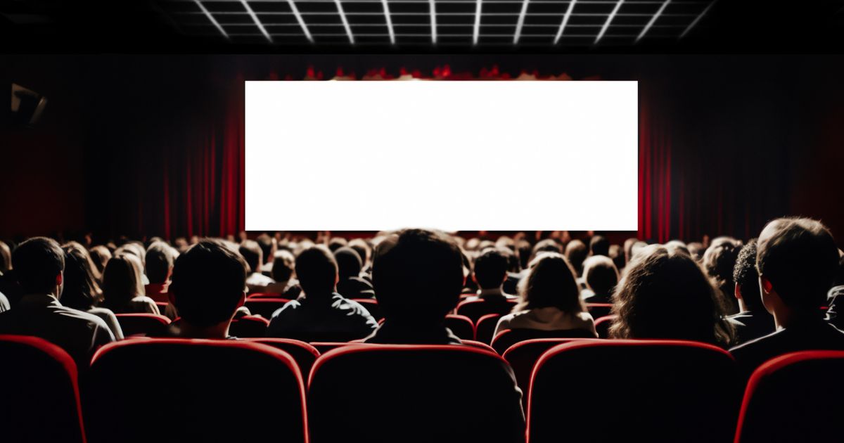 An audience sitting in front of a blank screen at a movie theater.