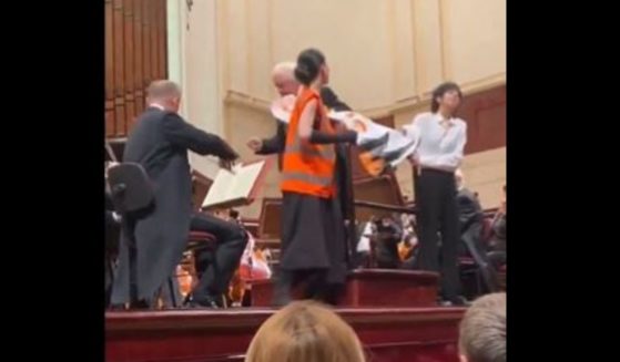 During a live orchestral concert in Warsaw, Poland, the conductor ripped a protest sign away from two climate change activists when they interrupted the perfomance. (@WojPawelczyk / X screen shot)