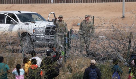 Texas National Guard members prevent illegal immigrants from Venezuela from moving beyond a barbed-wire fence into the United States near El Paso after they crossed the Rio Grande on Feb. 29.