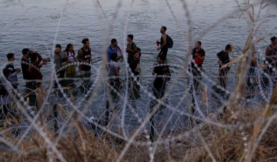 Illegal immigrants waiting in the Rio Grande to climb over concertina wire into the U.S.