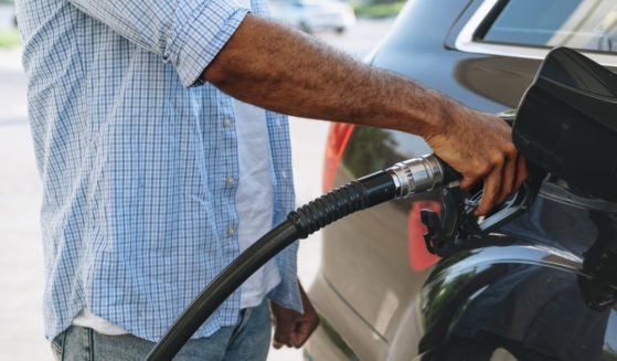 A stock photo shows a man pumping gas into his car.