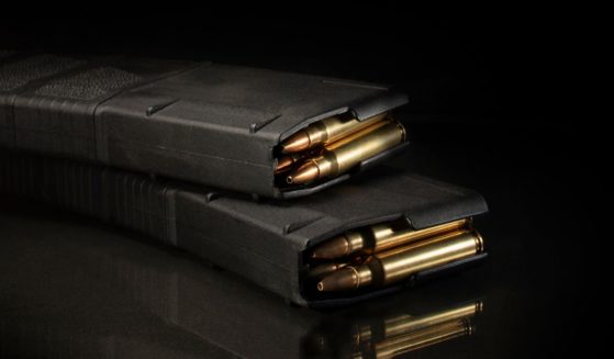 A stock photo shows a pair of AR-15 magazines loaded with ammunition on a black background.
