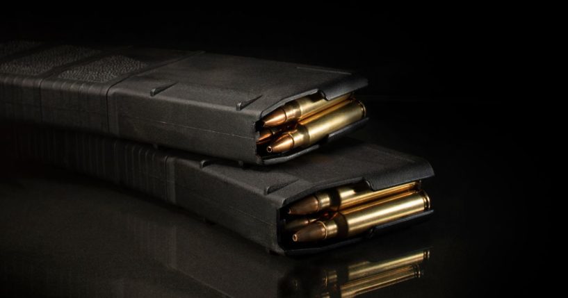 A stock photo shows a pair of AR-15 magazines loaded with ammunition on a black background.