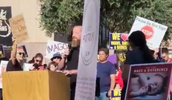 Pastor Jeff Durbin, center, of Apologia Church in Mesa, Arizona, was not deterred by an abortion protester, center, who shouted slogans as he prayed outside the state capitol building.