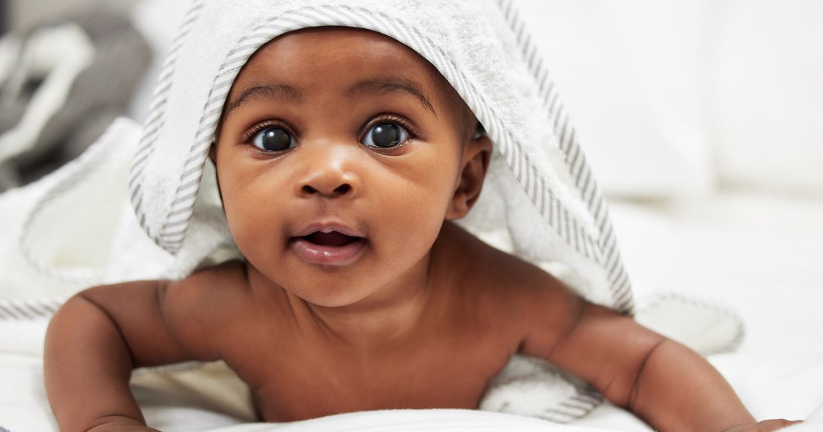 A baby is shown peeking out from under a towel.