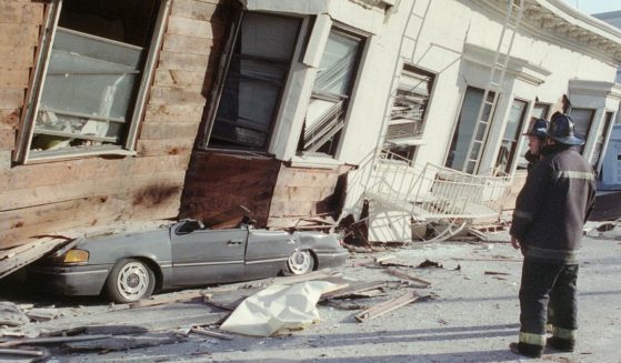 Two firemen survey the damage from a San Francisco house that collapsed, crushing a car, in the city's Marina District after a quake rocked California October 17, 1989.