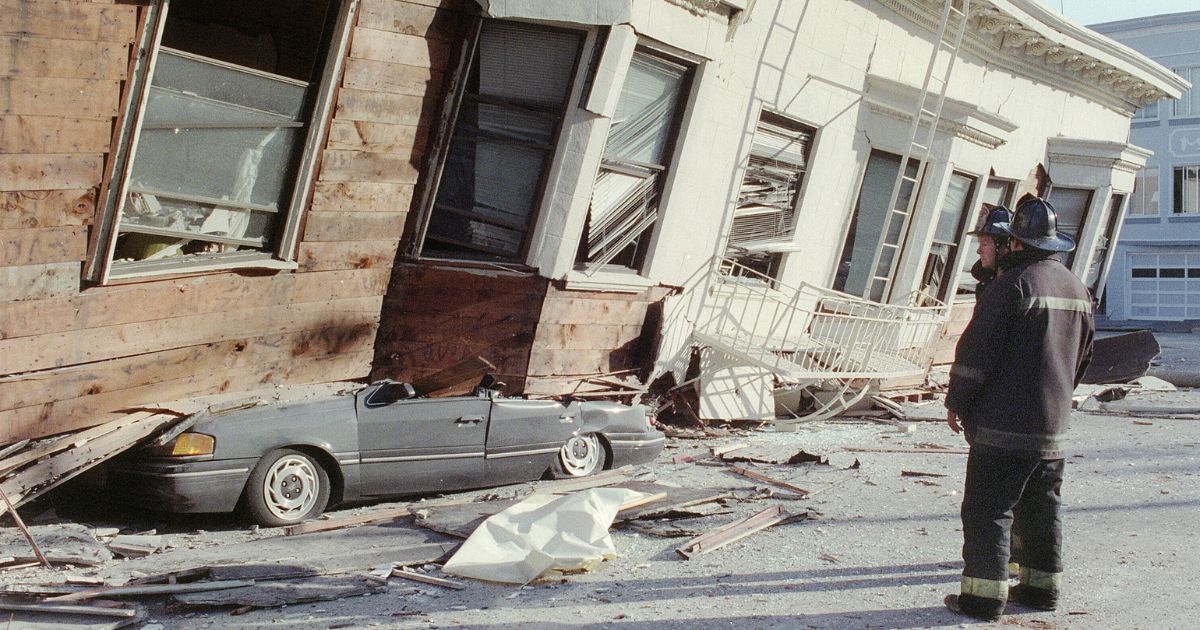 Two firemen survey the damage from a San Francisco house that collapsed, crushing a car, in the city's Marina District after a quake rocked California October 17, 1989.