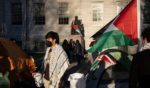 A student protester stands in front of the statue of John Harvard, the first major benefactor of Harvard College, draped in the Palestinian flag, at an encampment of anti-Israel demonstrators at Harvard University in Cambridge, Massachusetts on Thursday.