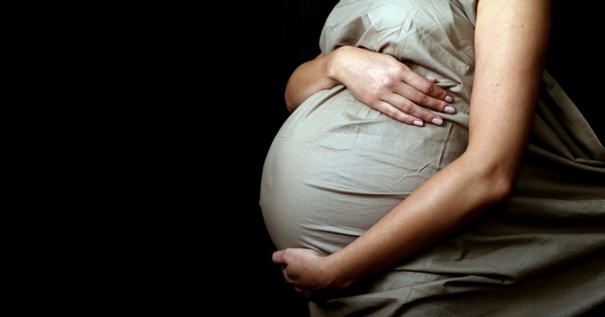This photo shows a pregnant mother holding her stomach.