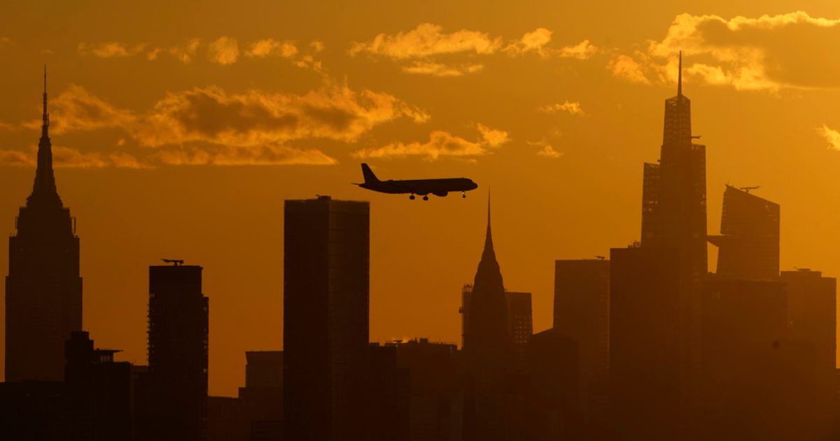 A plane is shown flying over the New York City skyline.