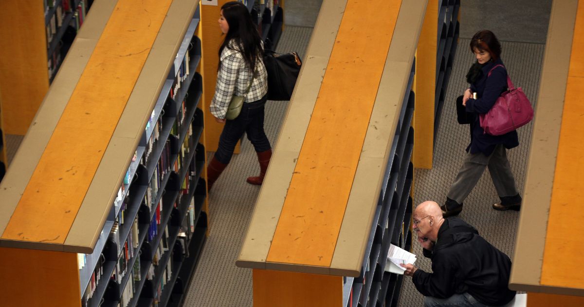 Patrons of the San Francisco Public Library in San Francisco, California, walk among the shelves and read a book on Jan. 11, 2011.