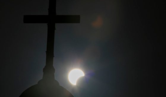 A partial solar eclipse is seen behind a cross on the steeple of the St. George church in downtown Beirut, Lebanon, June 21, 2020.