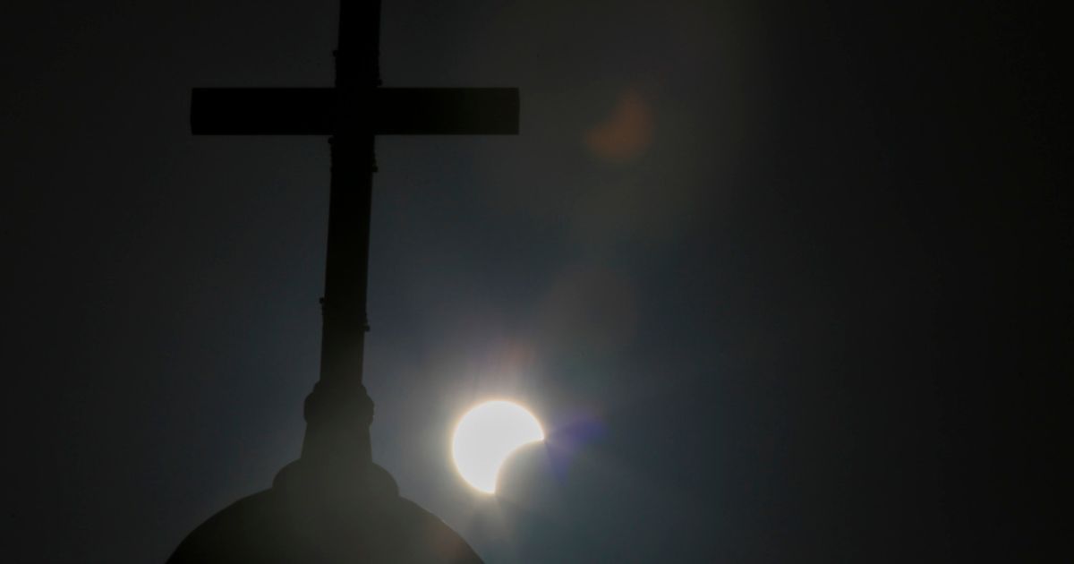 A partial solar eclipse is seen behind a cross on the steeple of the St. George church in downtown Beirut, Lebanon, June 21, 2020.