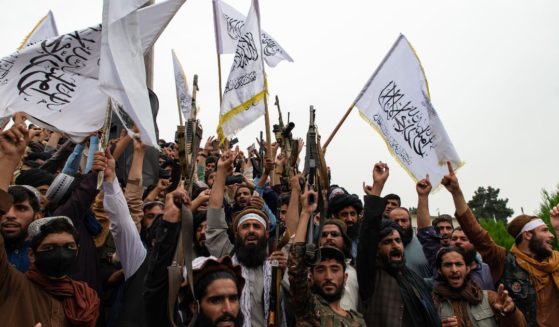 Men wave the flag of the Islamic Emirate of Afghanistan during a celebration of the first anniversary of the Taliban's return to power in Kabul, Afghanistan, on Aug. 15, 2022.