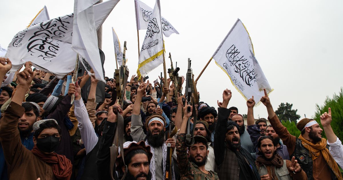 Men wave the flag of the Islamic Emirate of Afghanistan during a celebration of the first anniversary of the Taliban's return to power in Kabul, Afghanistan, on Aug. 15, 2022.