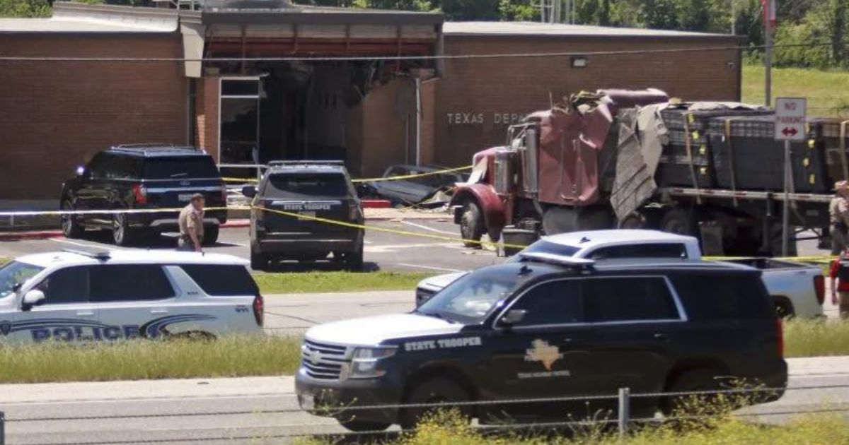 Emergency personnel work at the scene after an 18-wheeler crashed into the Texas Department of Public Safety Office in Brenham on Friday. A suspect has been arrested in connection with the incident.