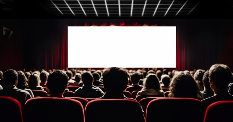 The audience of a full movie theater looking at a white screen.