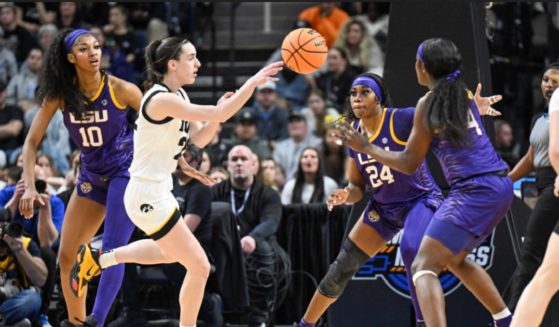 LSU players Angel Reese, left, center, and Flau'jae Johnson defend against Iowa guard Caitlin Clark as she passes the ball Monday during the first half of an Elite Eight college basketball game in the NCAA Tournament in Albany, New York.
