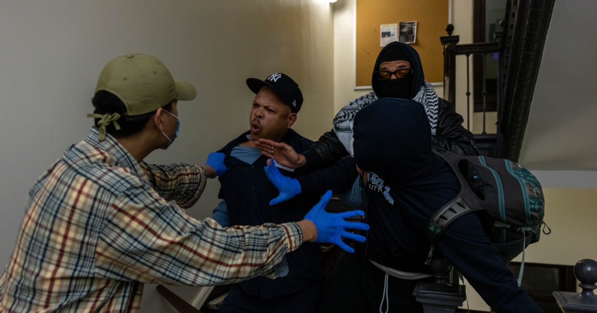 A maintenance crew member confronts rioters attempting to barricade themselves inside Hamilton Hall at Columbia University early Tuesday in New York City.