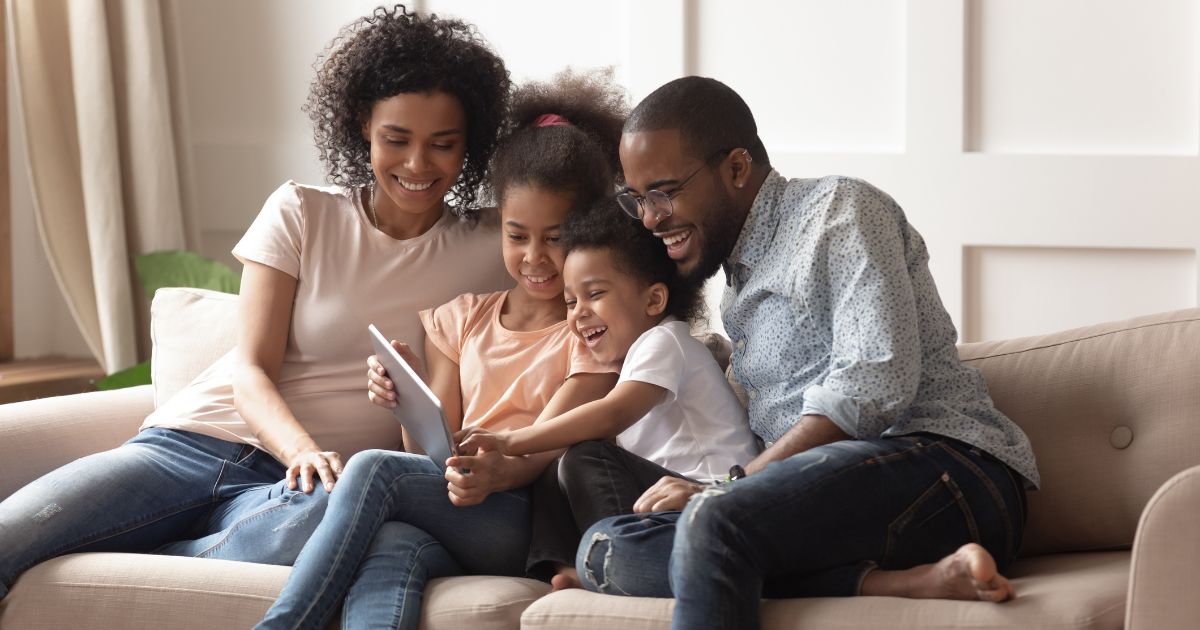 A stock photo shows a happy family sitting on the couch together.