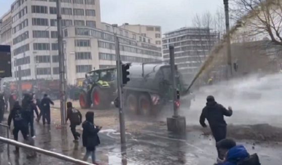 During a protest last week in Brussels, Belgium, farm vehicle sprays liquid manure while a police water cannon tries to disperse the waste.