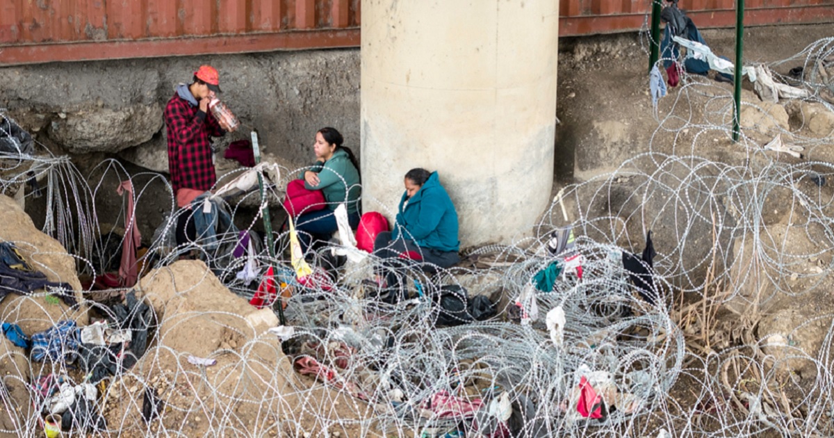 Migrants wait under an international bridge after crossing the Rio Grande from Mexico and passing through coils of razor wire on March 17 in Eagle Pass, Texas.