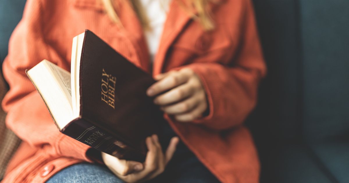 A stock photo shows a woman opening a Bible.