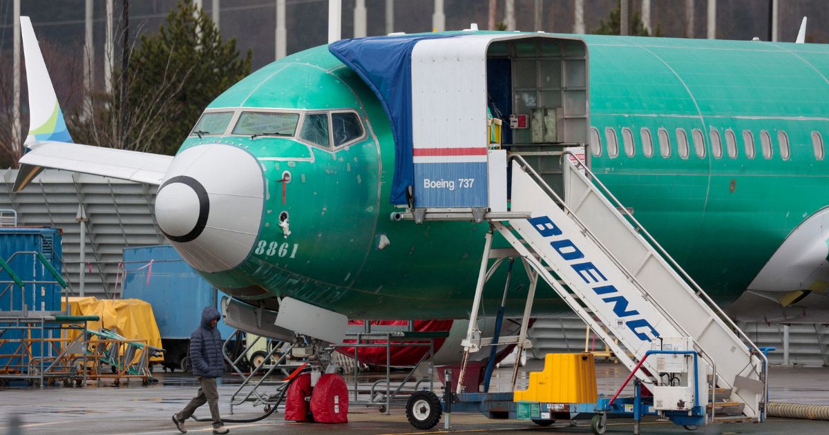 A man walks past an unpainted Boeing 737-8 MAX parked at Renton Municipal Airport adjacent to Boeing's factory in Renton, Washington, on Jan. 25.