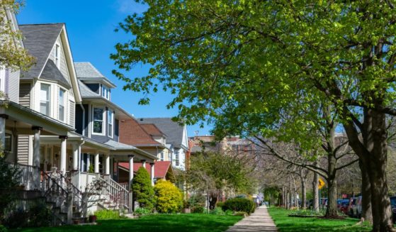 A row of old wooden homes with front lawns and a sidewalk is pictured in the North Center neighborhood of Chicago, Illinois.