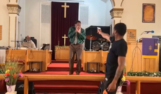 A man points a gun at Pastor Glenn Germany while he was preaching at Jesus' Dwelling Place Church in North Braddock, Pennsylvania, on Sunday.