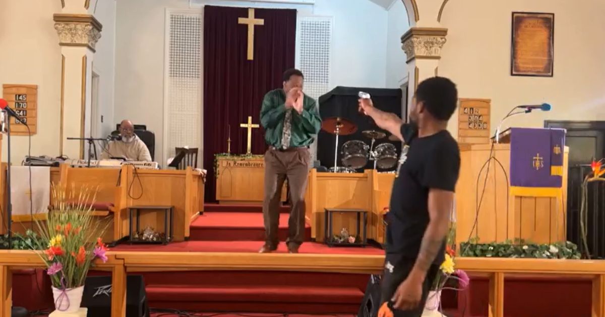 A man points a gun at Pastor Glenn Germany while he was preaching at Jesus' Dwelling Place Church in North Braddock, Pennsylvania, on Sunday.