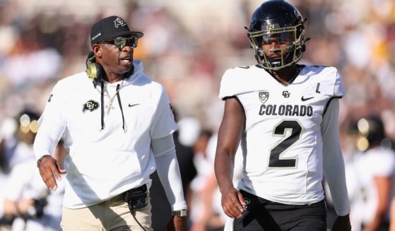 Head coach Deion Sanders of the Colorado Buffaloes talks with his son, quarterback Shedeur Sanders, during the NCAAF game against the Arizona State Sun Devils Oct. 7 in Tempe, Arizona.