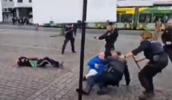 German police officers in Mannheim point their guns at a stabbing suspect on the ground, left, as others tend to wounded victims.