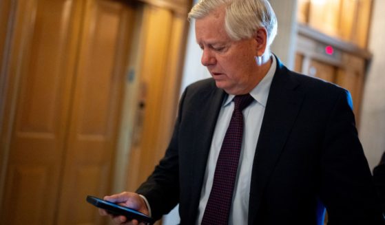 Sen. Lindsey Graham looks at his phone as he walks toward the Senate Chamber on Capitol Hill in Washington on April 23.
