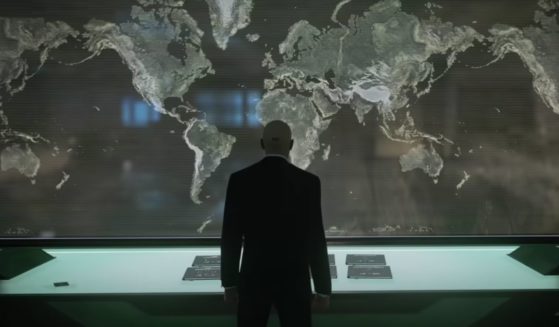 "Hitman" series protagonist Agent 47 looking at a map of the world.